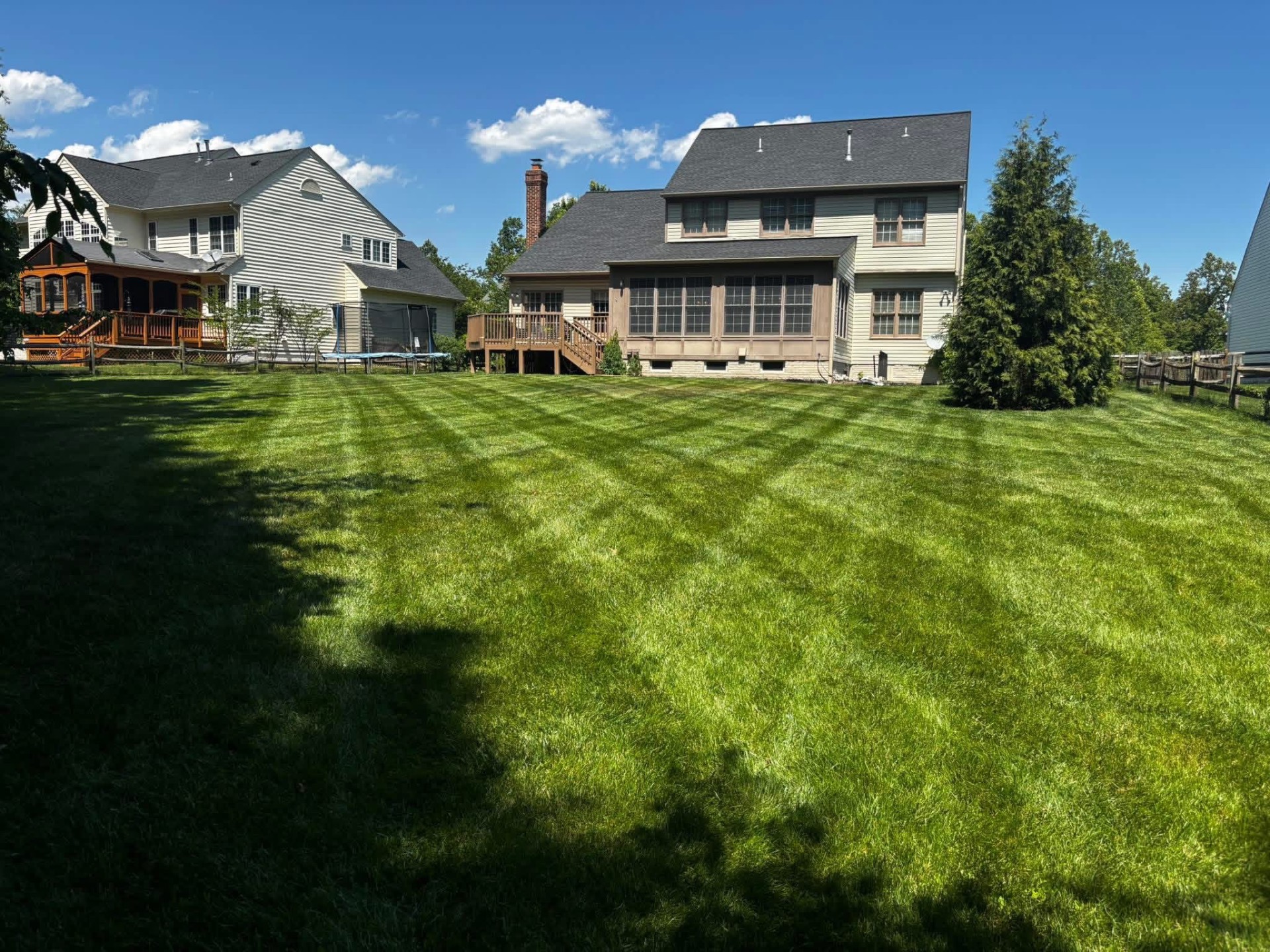 Striped backyard lawn with crisp mow lines behind a two-story home